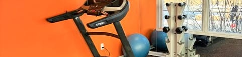 A treadmill is in a room with orange walls.
