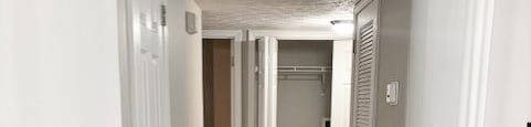 A hallway with white walls and a grey carpet.