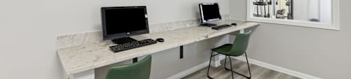 two computers on a desk in a room with a window