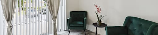 a living room with two green chairs and a ceiling fan