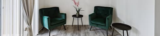 a living room with two green chairs and a ceiling fan
