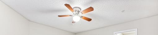 a spacious living room with carpet and a ceiling fan