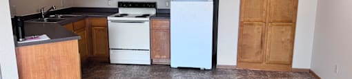 A kitchen with a white refrigerator and wooden cabinets.