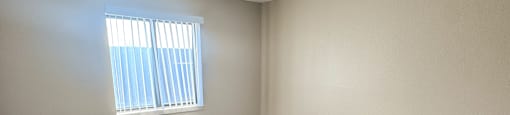 A room with a carpeted floor and a window with blinds.