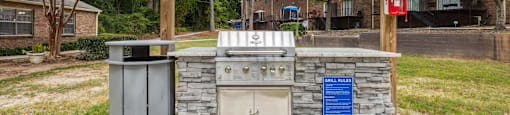 a covered patio with a barbecue grill and a trash can
