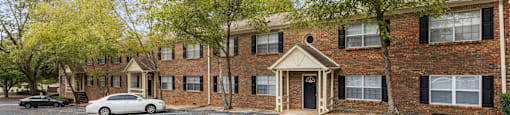 an empty parking lot in front of a brick apartment building