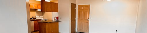 A room with a kitchenette and a door.