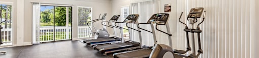 a gym with cardio machines and a ceiling fan