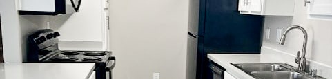 A kitchen with white cabinets and a black refrigerator.