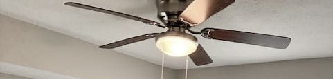 A room with a ceiling fan and a window with blinds.