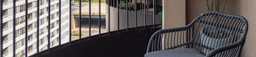 a balcony with two chairs and a table and a building in the background