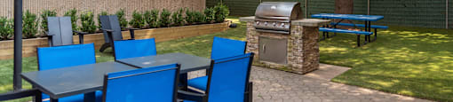 a patio with tables and chairs and a barbecue grill