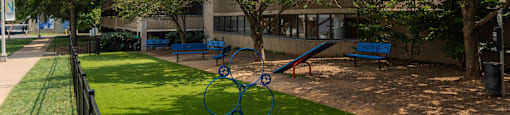 a playground with trees and benches in front of a building
