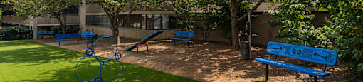 a park with benches and trees in front of a building