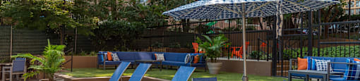 a patio with blue chairs and tables and an umbrella