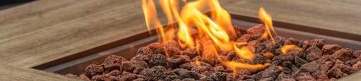 a fire pit on a wooden table with two orange chairs