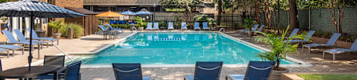 a swimming pool with blue chairs and a building in the background
