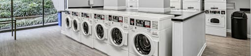 a laundry room with washers and dryers and a row of washing machines