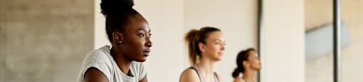 Three women are doing push-ups in a row in a gym.