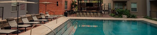 an apartment pool with a sunset in the background at The Can Plant Residences at Pearl, San Antonio, Texas