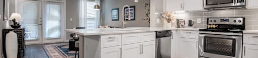 a kitchen with white cabinets and stainless steel appliances at The Can Plant Residences at Pearl, San Antonio