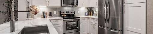 a white kitchen with stainless steel appliances and white cabinets at The Can Plant Residences at Pearl, San Antonio