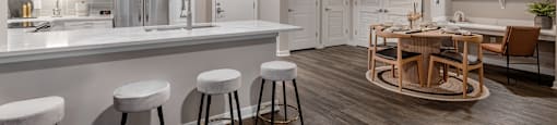 an open kitchen and living room with a bar and stools at The Can Plant Residences at Pearl, San Antonio, 78215