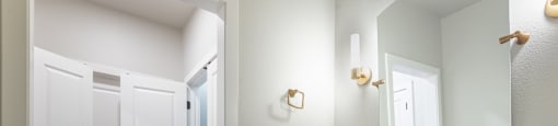 A bathroom with white cabinets and a gold faucet.