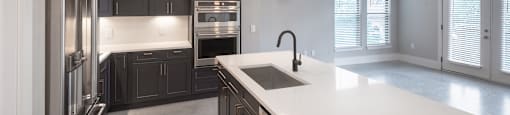 A modern kitchen with a white countertop and stainless steel appliances.
