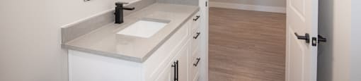 A bathroom with a sink, mirror, and wooden floor.