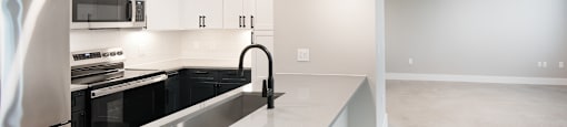 A modern kitchen with a white countertop and black appliances.