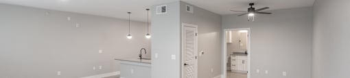 A spacious room with a ceiling fan and a kitchenette in the background.