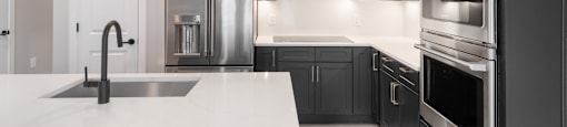 A modern kitchen with black cabinets and stainless steel appliances.