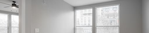 A room with a ceiling fan and a window with blinds.