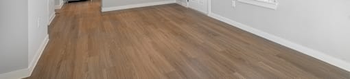 an empty living room and kitchen with white walls and wood floors