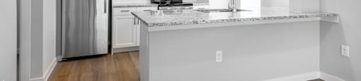 an empty kitchen with an island and stainless steel refrigerator