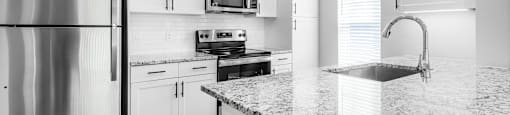 a kitchen with white cabinets and granite counter tops and a stainless steel refrigerator