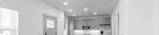 a living room and kitchen with white walls and wood floors