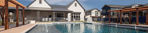 a large swimming pool with a house in the background