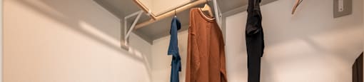 a well lit closet with coats hanging on a rack