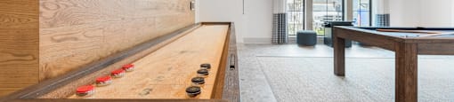 a game room with a shuffleboard table and a pool table