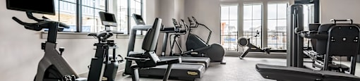 A gym with a variety of equipment including treadmills, weights, and a television.