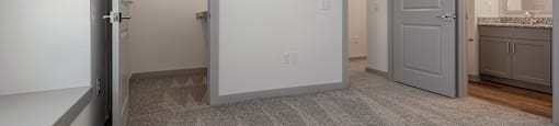 A carpeted room with a doorway leading to another room.