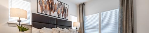 A bedroom with a large bed and a painting on the wall.