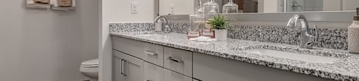A bathroom with a marble countertop and a mirror above it.