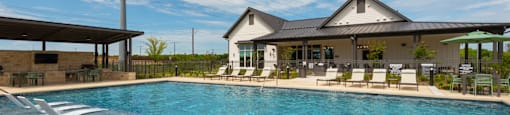 A pool with a blue line in the middle and white chairs around it.