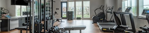 A spacious gym with a variety of equipment including treadmills, weight machines, and a bench press.