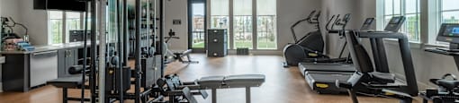 A spacious gym with a variety of equipment including treadmills, weight machines, and a bench press.
