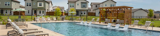 A pool surrounded by lounge chairs and a wooden structure in the middle of the pool.