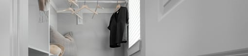A small closet with a coat hanging on a rod.
